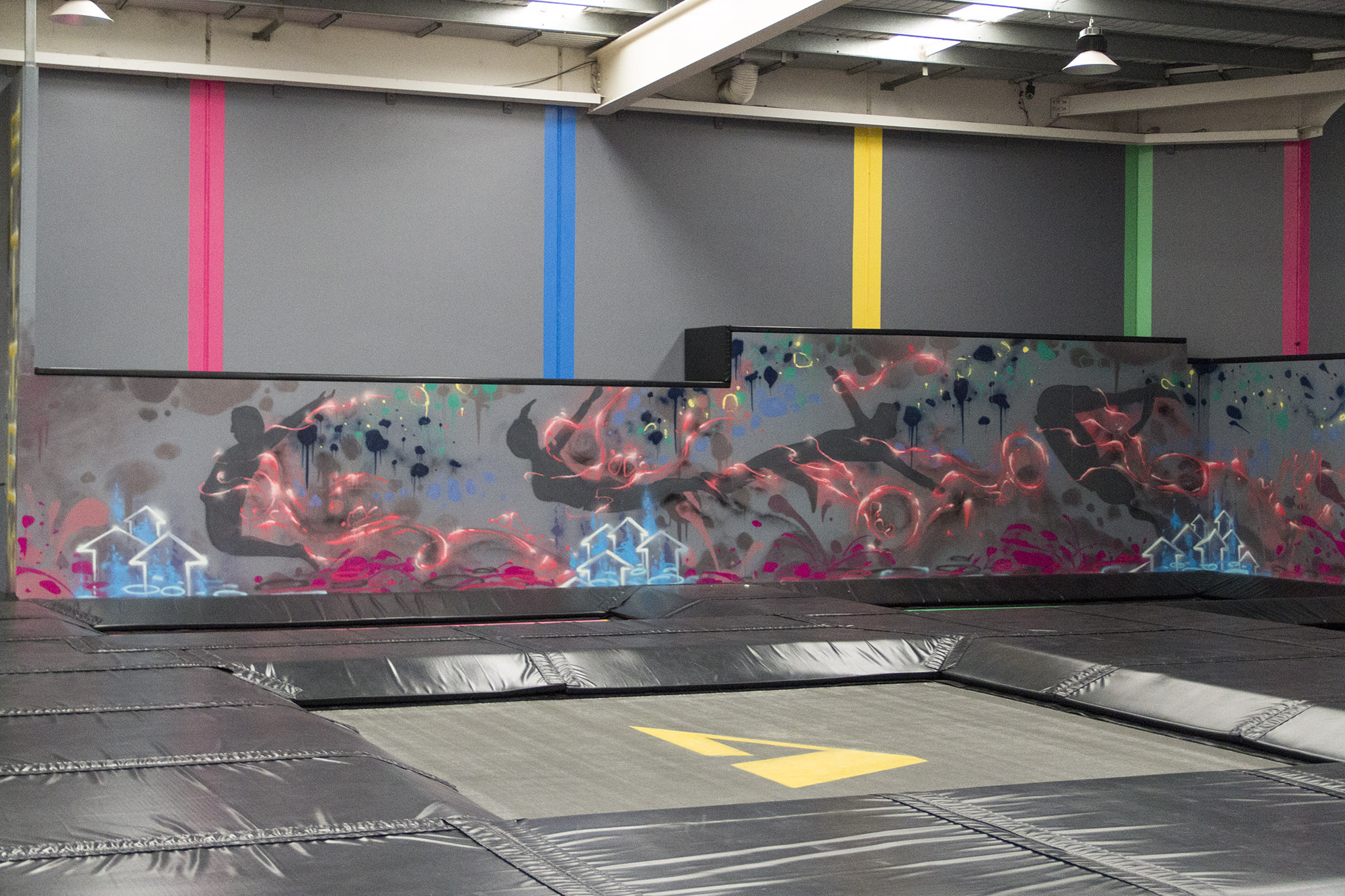 Airborne trampoline park interior decorated with urban graffiti and wall murals.