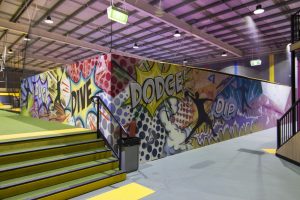 Airborne trampoline park interior decorated with urban graffiti and wall murals.