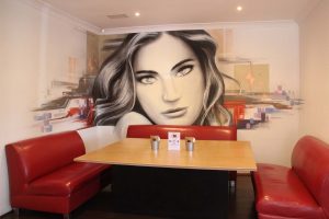 Graffiti mural portrait inside restaurant.