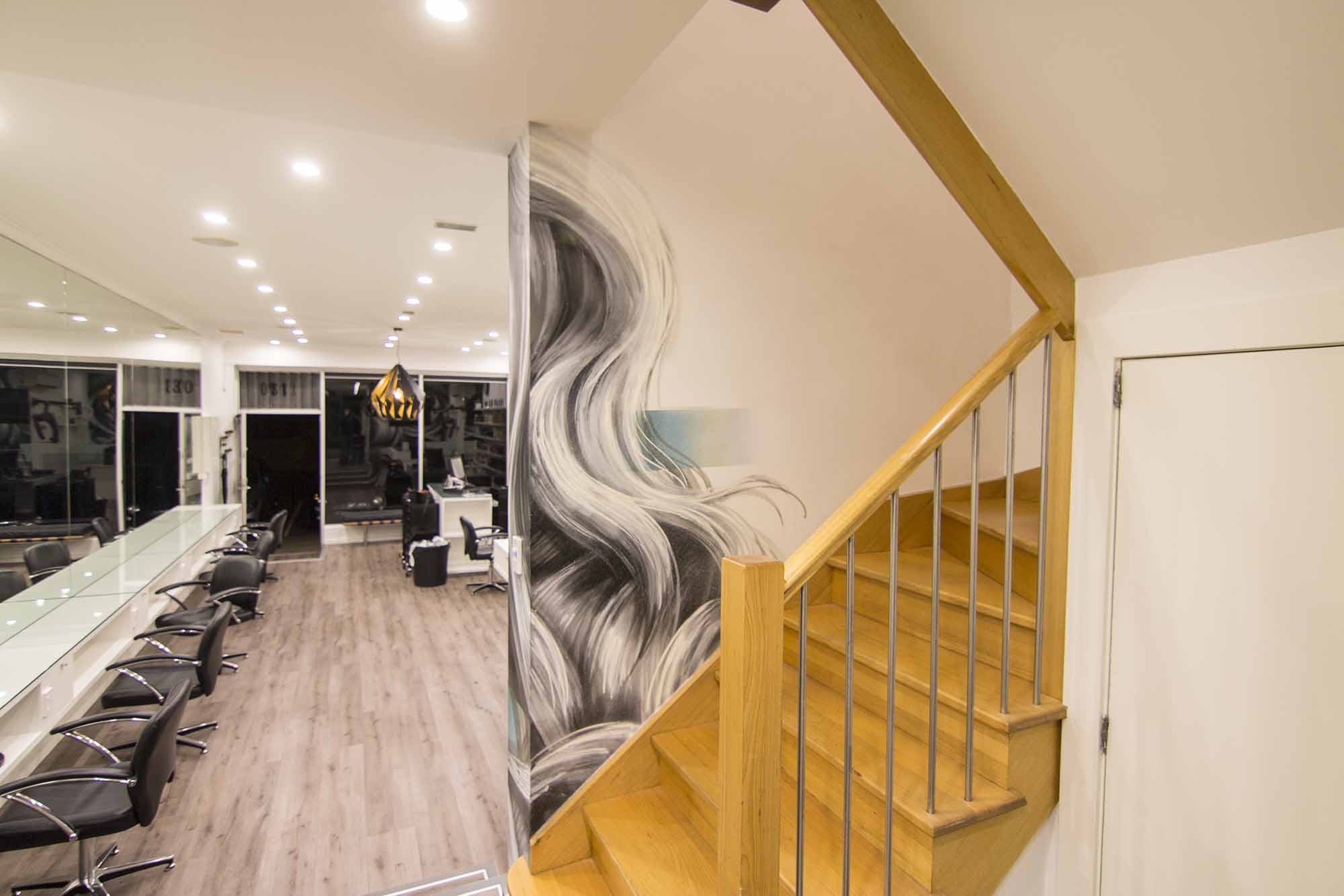 Interior of hair salon decorated with wall mural featuring textured strands of hair.