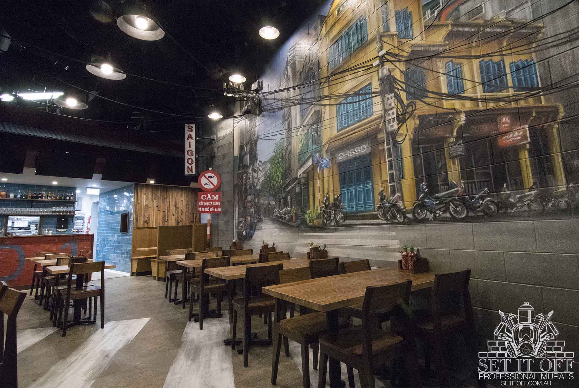 Continuous wall murals throughout a Vietnamese restaurant combined with other recycled materials and sculptures.