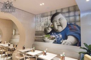 An interior wall mural based on the Yo I'm Busy Eating Pho meme in a restaurant.